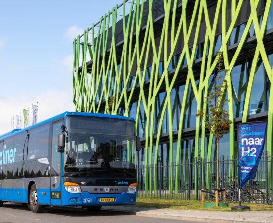 Decoratieve afbeelding van een bus die voor het Hive.Mobility gebouw langsrijdt
