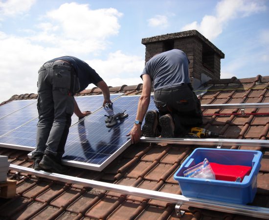 Sfeerbeeld van installateurs die zonnepanelen op een dak monteren.