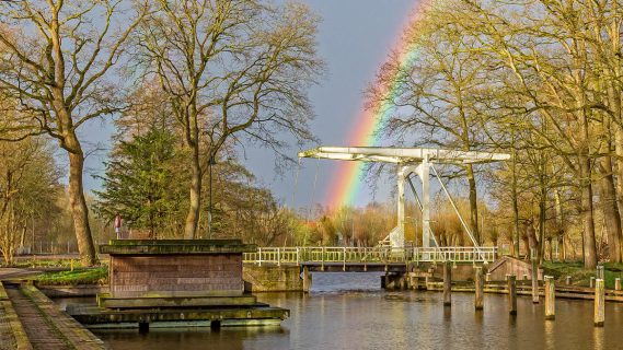 Sfeerbeeld van een bruggetje met regenboog op de achtergrond in Slochteren.