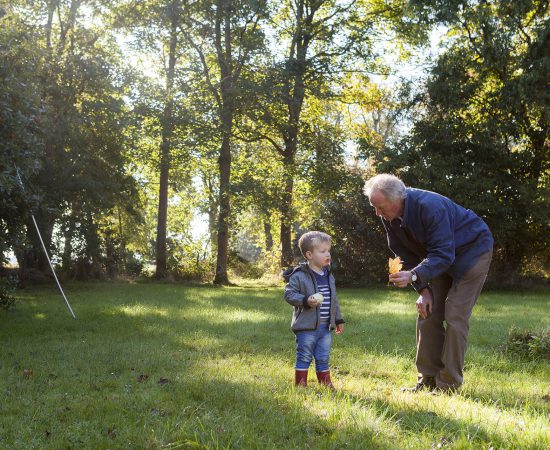 Sfeerbeeld van een opa met zijn kleinzoon die buiten aan het spelen zijn. De opa houdt een blaadje vast.