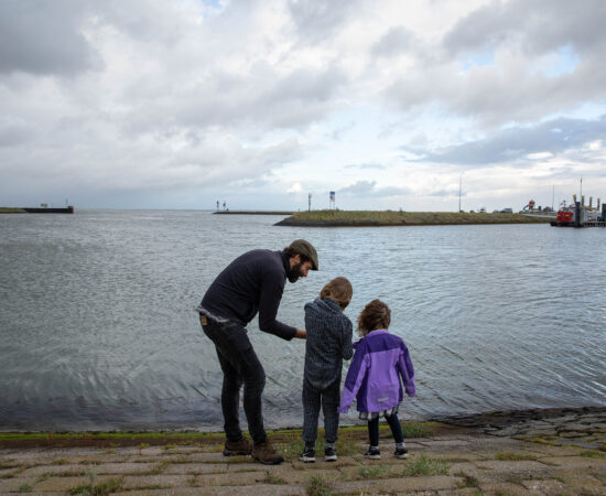 Decoratieve afbeelding van een vader met twee kinderen bij het water in Lauwersoog