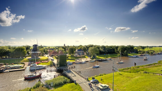 Sfeerbeeld voor het thematisch programma van de brug in Garnwerd die openstaat(Winsum) met huizen aan het water en bootjes in het water