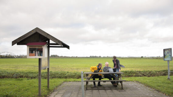 Initiatiefnemers van het Toukomstproject Touripedia staan in het Groninger Landschap over hun laptop heen gebogen